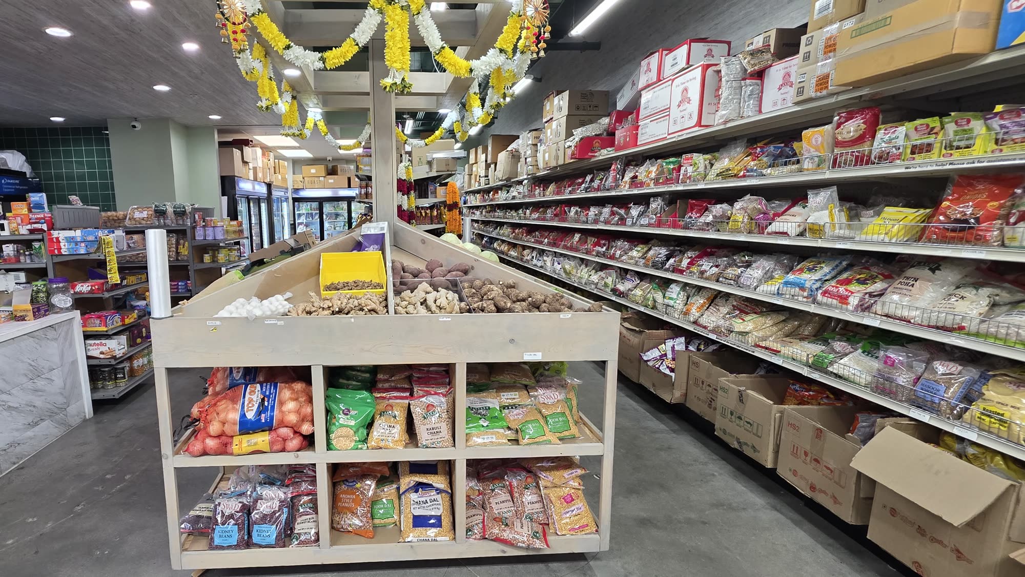 Inside Desi Deli: marigold garlands over the fresh produce station and stocked aisles